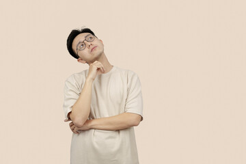 Thoughtful Young asian Man Contemplating Ideas While Standing Against a Neutral Background