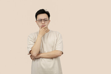 Thoughtful Young asian Man Contemplating Ideas While Standing Against a Neutral Background