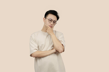 Thoughtful Young asian Man Contemplating Ideas While Standing Against a Neutral Background