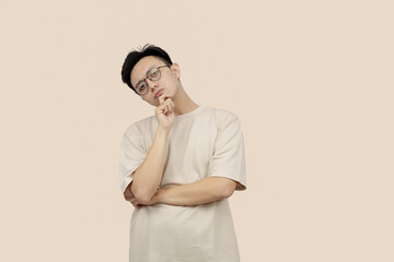 Thoughtful Young asian Man Contemplating Ideas While Standing Against a Neutral Background