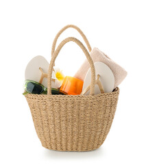 Wicker bag with bottle of sunscreen cream and beach accessories isolated on white background