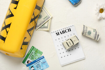 Calendar with taxi roof sign, driver's licenses, money and toy cars on white grunge background