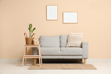 Interior of living room with sofa, blank frames and stool