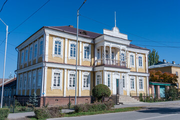Obraz premium Historic building with yellow walls and white ornate trim in Karakol in sunny weather. 