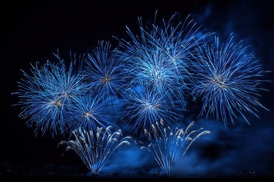 Colorful blue fireworks burst in the night sky. The display features various shapes and sizes, illuminating the dark background with vibrant colors.