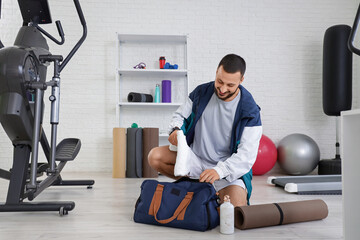 Young man with towel from sports bag at gym