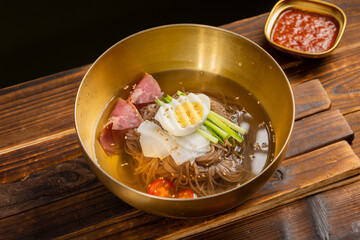 Korean Mul Naengmyeon (Cold Buckwheat Noodles in Icy Broth) – Traditional Korean Summer Dish with Tangy Chilled Soup, Sliced Beef, Cucumber, Egg, and Mustard, Served in a Stainless Bowl
