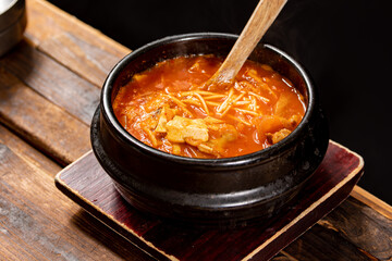 Korean Soft Tofu Stew (Sundubu Jjigae) in a Hot Stone Pot – Traditional Spicy Korean Soup with Silken Tofu, Egg, Vegetables and Red Chili Broth

