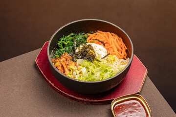 Hot stone pot Korean bibimbap with spicy pork (Jeyuk), kimchi, vegetables, and fried egg. A sizzling dolsot bowl filled with bold flavors, ready to be mixed with gochujang and sesame oil for a classic