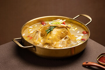 Traditional Korean whole chicken hot pot (Dakhanmari) served in a large pot with clear broth, green onions, garlic, and potatoes. A healthy and hearty soup enjoyed for its clean flavor and tender meat