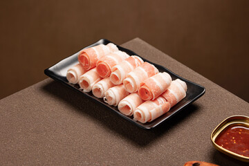 Thinly sliced Korean pork belly (Daepae Samgyeopsal) arranged on a plate, ready to grill. A popular Korean BBQ meat known f
