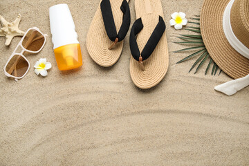 Composition with beach shoes, bottle of sunscreen cream and beach accessories on sand as...