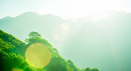 Emerald green mountains bathed in sunlight create a serene landscape, perfect for backgrounds and nature themes.
