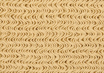 Overhead view presents a texture of wavy dried noodles, featuring a raw ingredient for an Asian cuisine meal.