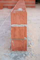 Start of a sustainable brick wall with thermal clay blocks and guide string, marking the first step toward a dream home.