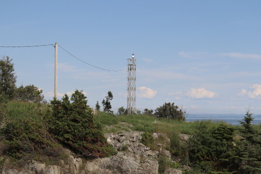 A new and modern lighthouse on a coastline in Charlevoix. Charlevoix landscape in summer and in Quebec and Canada country. A riverside with a panorama. Lighthouse for maritime transportation.