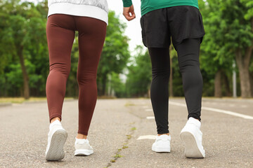 Fototapeta premium Sporty woman with personal trainer running outdoors, back view