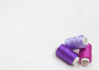 Three Purple Thread Spools on Cream Background with Copy Space