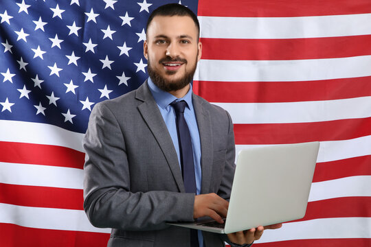 Young businessman with laptop against USA flag. Labor Day celebration