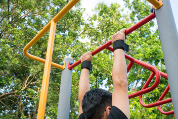 Man doing pull ups workout on the steel bar in the park.