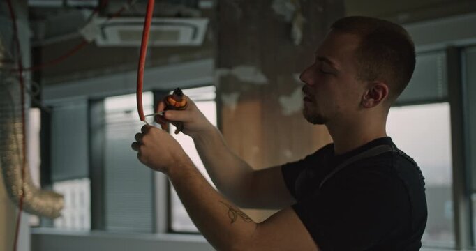 An electrician installs a fire alarm in a modern office building under construction. The scene emphasizes safety and professionalism in the workplace.