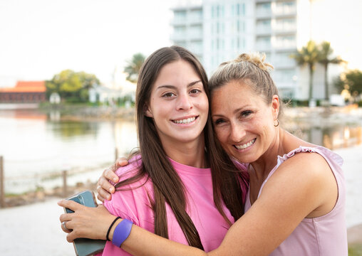 A mother and a daughter embrace and smile together outdoors. Fun active lifestyle photo showing family love and bonding while on a family vacation