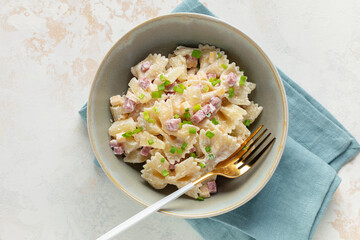 Salad with pasta, ham, pineapple, onion, cheddar cheese with sauce in a bowl on the table. Hawaiian cuisine