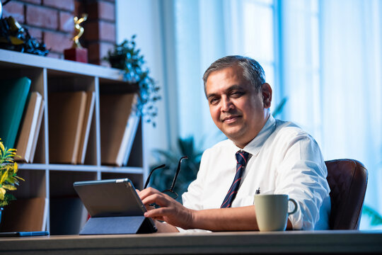 Asian businessman uses tablet computer while sitting in sleek office workspace - Powered by Adobe