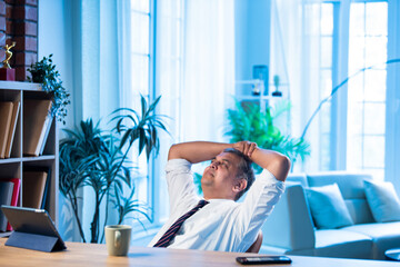 Asian executive leans back on chair at office desk, taking a break from work