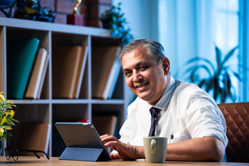 Asian businessman uses tablet computer while sitting in sleek office workspace
