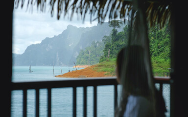 Blurred of a woman on floating raft house looking at a river and mountains view