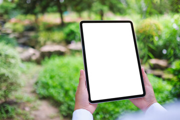 Mockup image of a woman holding digital tablet with blank white desktop screen in the nature...