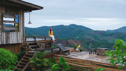 A woman sitting on wooden terrace and looking at a mountain view