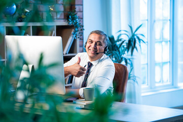 Indian call center agent wearing headset and working on computer in corporate office