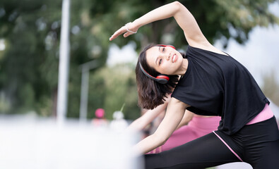 Two young women in workout clothes are exercising together in a park.