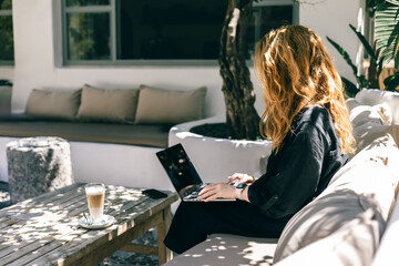 Freelance Woman Working on Laptop Outdoors with Coffee in Peaceful Garden Patio Setting