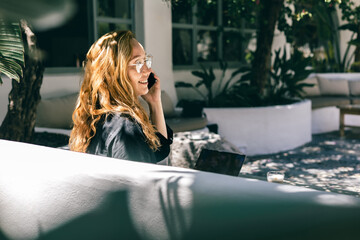 Smiling Woman with Red Hair Talking on Phone in Outdoor Garden Office with Natural Light