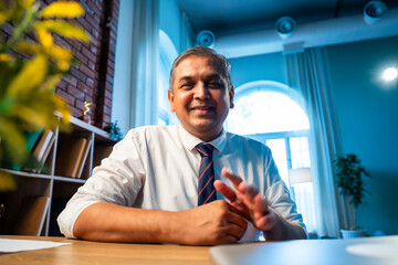 Confident Indian businessman on video call with client in stylish corporate office