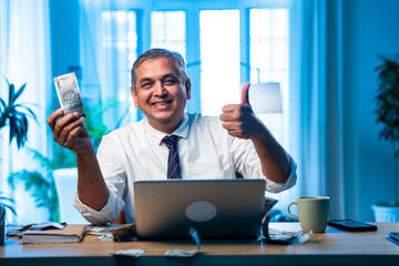 Indian executive reacts as money rains over him while working on office computer