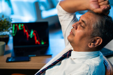Indian investor appears stressed after stock market crash, laptop shows falling graph