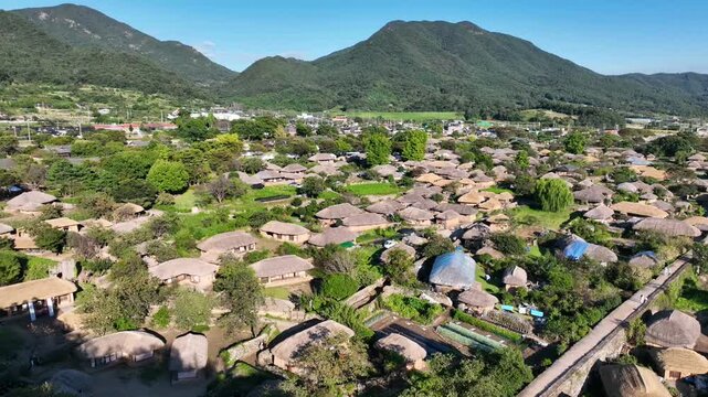 Drone tracking shot of a historic village with thatched roofs and surrounding greenery