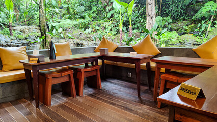 A stylish modern living room interior featuring a curved grey sofa, a maroon accent chair, and a beige armchair arranged around unique geometric coffee tables. 