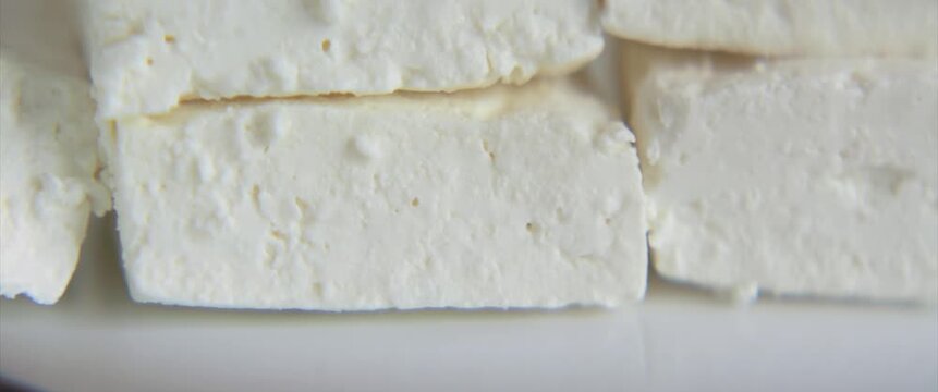 Tasty pieces of cheese of white plate anamorphic 4k sliding video