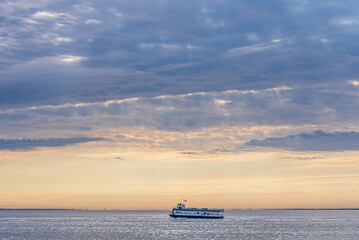 A ferry crosses the water during sunset. Shot in Fire Island, New York State, United States of America.