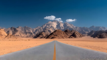 Fototapeta premium A stunning desert landscape features a long empty road leading toward majestic mountains under a clear blue sky with a few fluffy clouds.