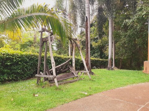 A wooden chair in a park in a state of disrepair