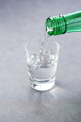 韓国の伝統的な蒸留酒、よく冷えた韓国焼酎（ソジュ）をグラスに注ぐ