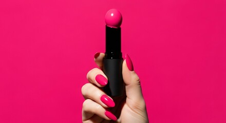 Hot pink lipstick beauty product held by hand with matching nails on bright pink background closeup shot