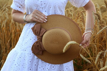 Girl in a white dress in a wheat field at sunset