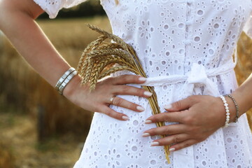 Girl in a white dress in a wheat field at sunset